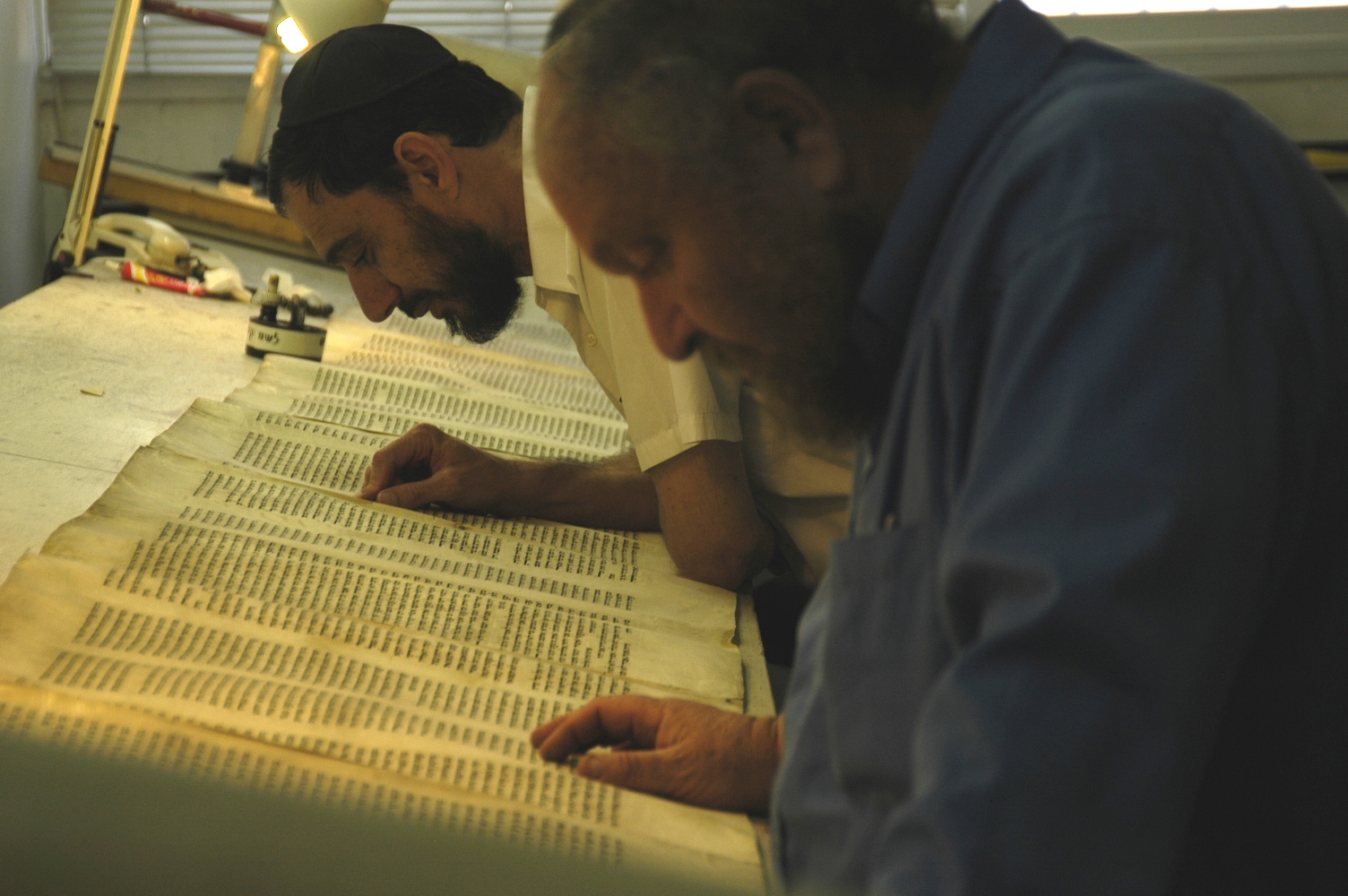 上图：两位耶路撒冷的文士正在校对妥拉经卷（Torah Scroll）。希伯来圣经抄写员被称为文士（Sofer/Sofrim），意思是「字母数算者」。神拣选了一批敬虔、严谨的文士把摩西五经（妥拉）抄传了3500年，在304,805个字母中，只有6个不太重要的字母存在疑问。文士必须遵守超过4000条犹太律法，每个笔画什么地方粗、什么地方细，什么字母必须变大、什么字母必须变小，什么字母必须添加单顶皇冠，什么字母必须添加三顶皇冠，都有具体规定。因此，只有最虔诚的正统犹太人才有资格做文士，他们抄写妥拉就像建造会幕一样认真。
