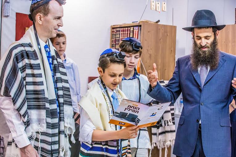 上图：一个犹太男孩在成为「诫命之子 Bar Mitzvah」的成人礼上诵读经文，他的前额上带着经文匣（Tefillin），身上披着祷告巾（ Tallit）。犹太教男孩到了13岁，在律法上就和成年人有同样的权利和义务，被称为「诫命之子」。「诫命之子」每天都必须佩戴经文匣，并被安排在会堂中诵读妥拉、先知书和唱颂圣歌，带领聚会和公祷。犹太男孩在成人礼之前，由父母在神面前为自己的行为负责，而在成人礼之后，必须自己向神负责。因此，只有「诫命之子」，才可以「向耶和华许愿或起誓，要约束自己」（民三十2）。