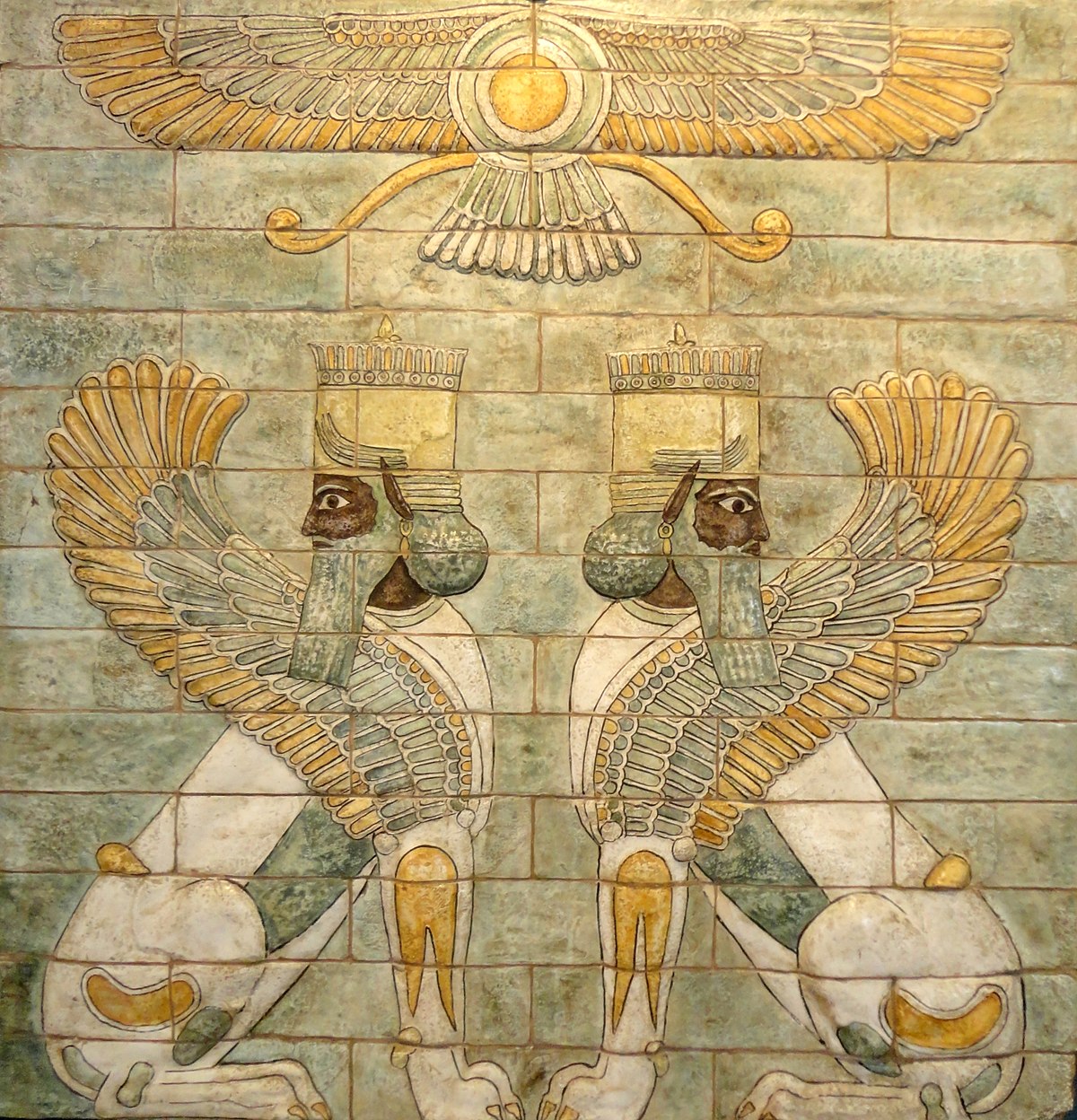 上图：书珊城大流士一世王宫里的彩釉砖装饰面板。在蓝绿色的地面上坐着一对带翼狮身长须人，在它们上方盘旋着Ahura-Mazda（Ahura-Mazda）神的翼状盘，这是当时典型的波斯风格。