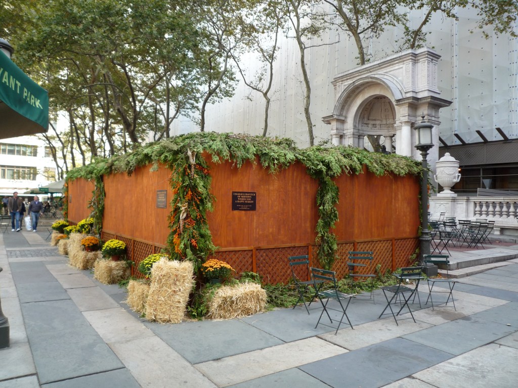 上图：纽约街头的住棚节棚子（Sukkah），上面只有一层薄薄的树叶，与周围坚固的屋顶形成鲜明对比。